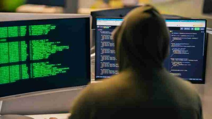 A person in a hoodie coding on dual monitors, depicting cybersecurity and hacking themes., tags: modular-ds-plugin-sicherheitslücke gefährdet - pexel